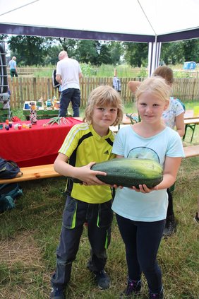 Schulkinder halten Riesen-Zucchini vom Gemüseacker
