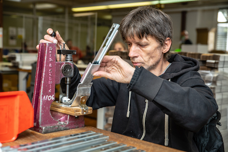 Mann mit Behinderung montiert Kleinteile an Metallstange