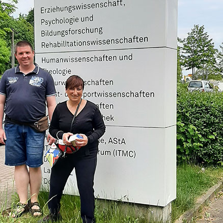Zwei Menschen mit Behinderung vor Eingangsschild der technischen Uni in Dortmund